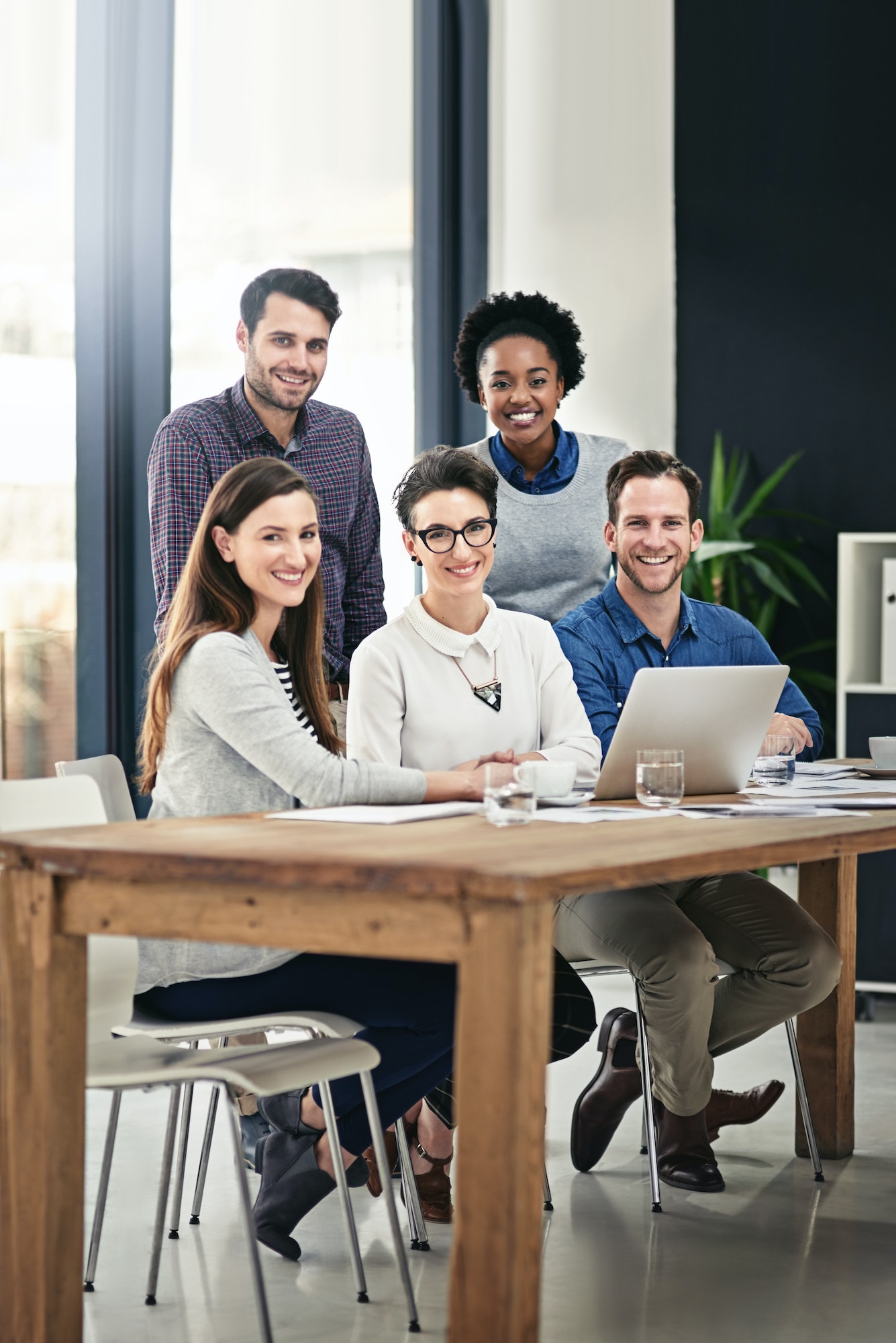 full-length-portrait-of-a-group-of-businesspeople-gathered-around-a-laptop-in-the-office.jpg